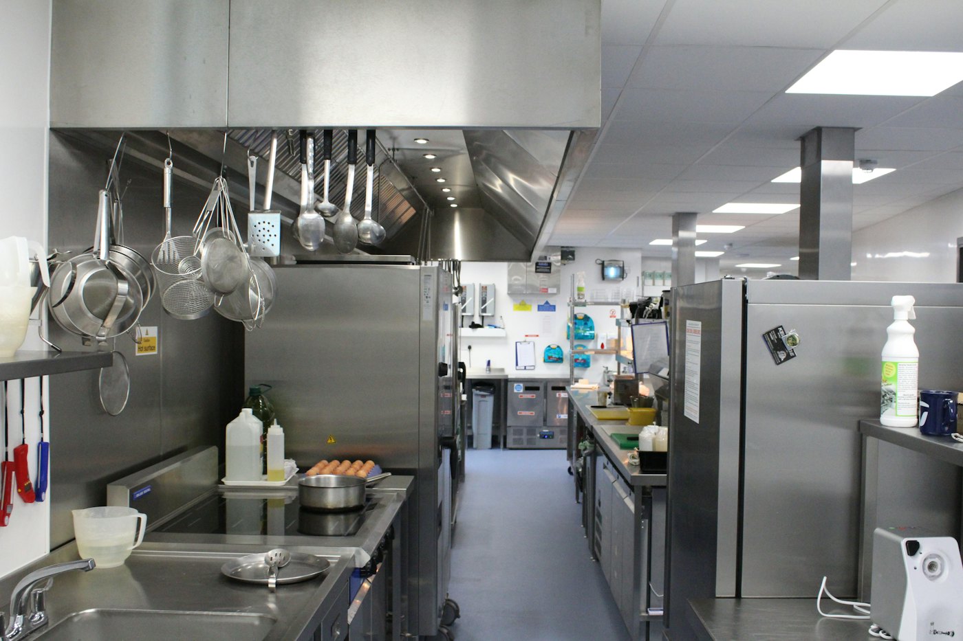 Commercial kitchen with stainless exhaust hood and hanging utensils