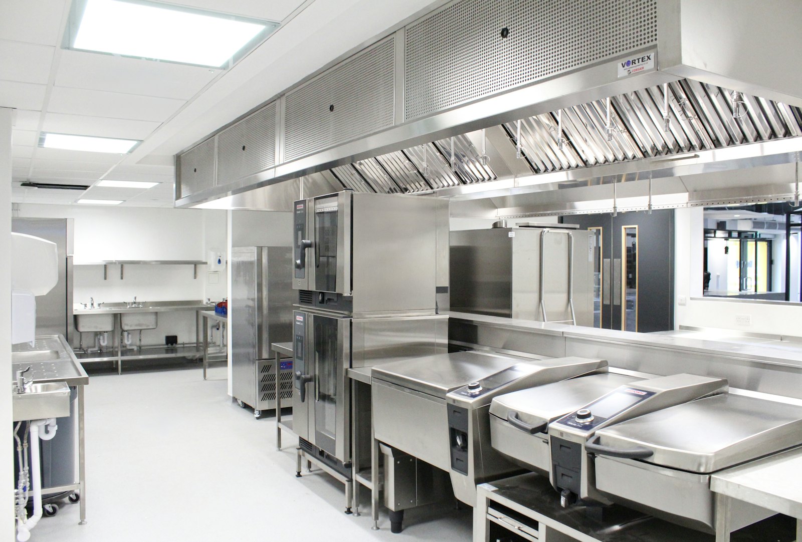 Long stainless steel exhaust canopy over a commercial cooking line