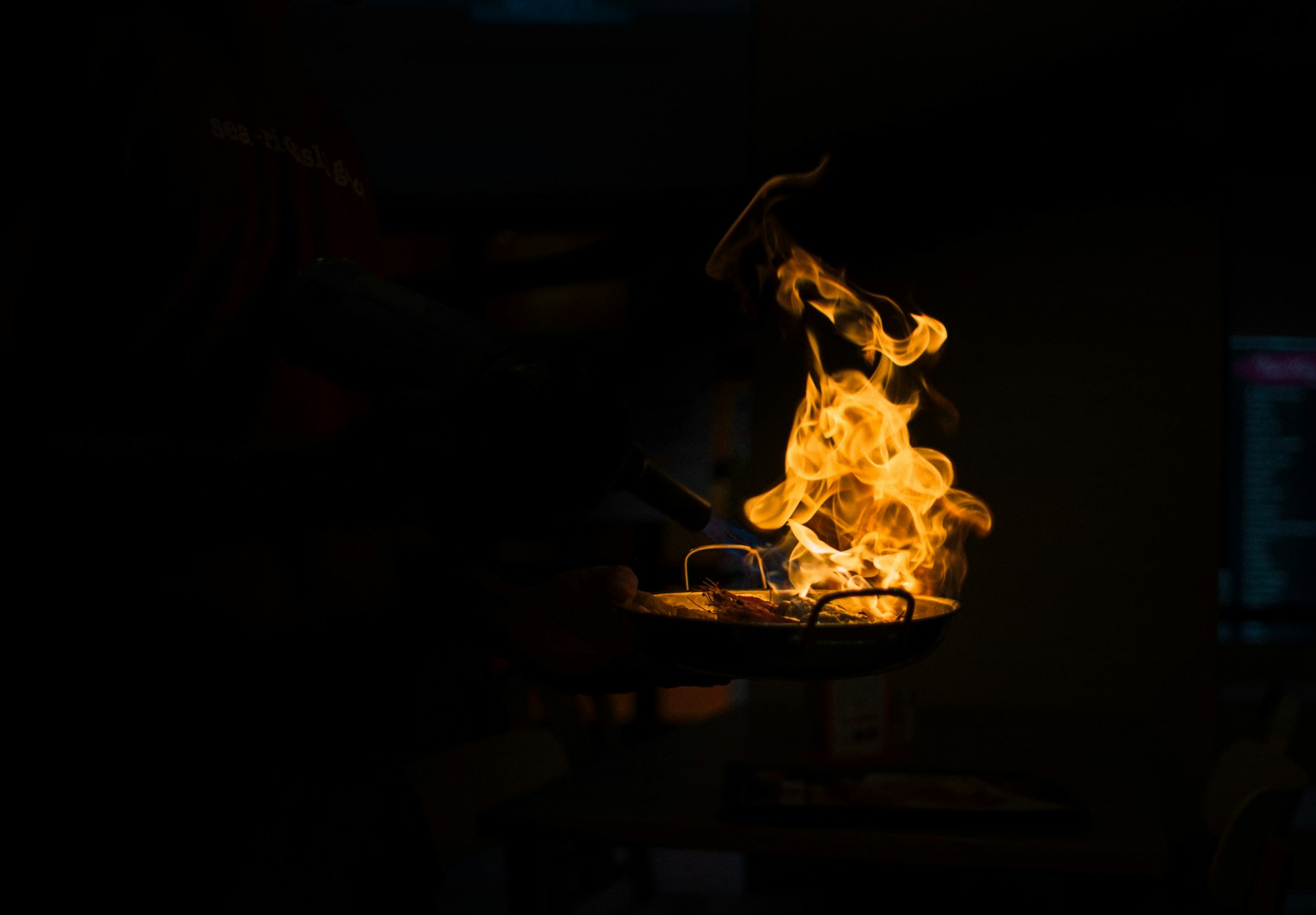 Flame flaring from a pan in a dark kitchen