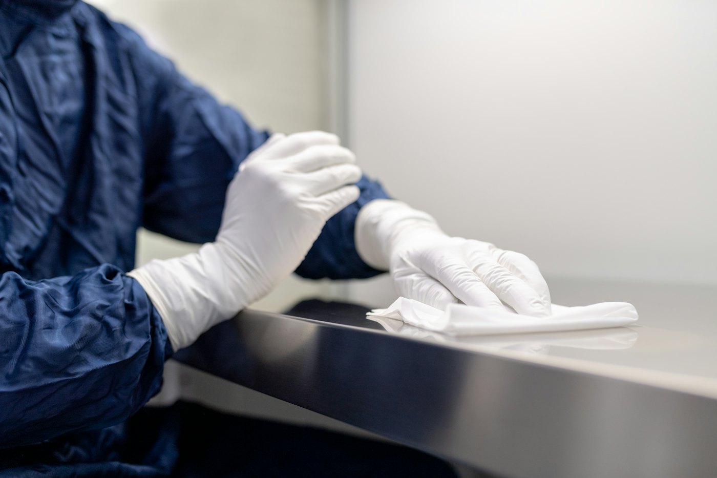 Gloved hand wiping a stainless steel surface